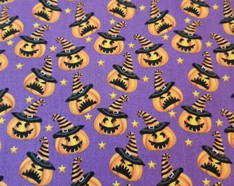May include: A repeating pattern of orange jack-o'-lanterns wearing black witch hats with orange and black stripes, set against a purple background with small yellow stars. The pumpkins have smiling faces.