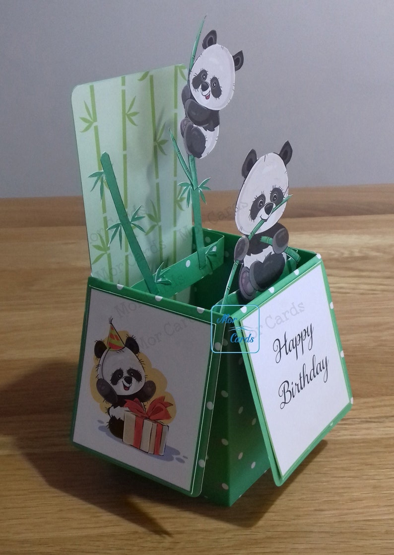 May include: A green and white pop-up card with a panda bear theme. The card features a panda bear holding a gift and the text "Happy Birthday".