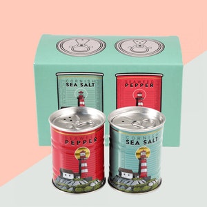 May include: Two metal salt and pepper shakers shaped like cans. The shakers are red and blue with a lighthouse design and the text "Seaweed Pepper" and "Cornish Sea Salt".