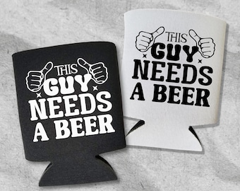 May include: Two beer can coolers, one black and one white, are displayed. Each cooler has the phrase "THIS GUY NEEDS A BEER" in bold, white lettering, with thumbs-up illustrations. The coolers are designed to keep beverages cold.