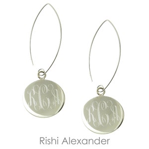 May include: A pair of silver dangle earrings with a round disc charm featuring a monogram. The earrings have a simple, elegant design.