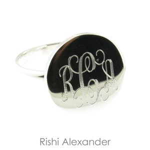 May include: A silver ring with a round, engraved top. The engraving is a monogram of the letters "R.A."