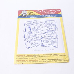 May include: A package of iron-on transfers featuring seven designs of blue and white chinaware with the days of the week written on each piece. The package is yellow and white with the text "Aunt Martha's Hot Iron Transfers" and "3764 - Fine Chinaware".