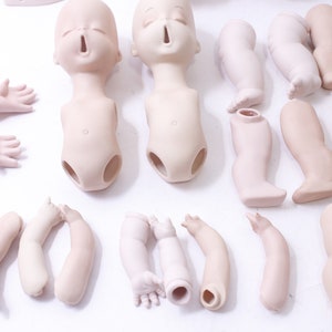 May include: A set of porcelain doll parts, including two heads, two torsos, six arms, and six legs. The parts are unpainted and ready to be customized.