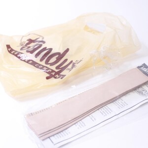 May include: A pack of leather strips for crafting projects, labelled "Leather Project" and featuring the Tandy Leather Company logo. The strips are beige and come in a clear plastic bag.