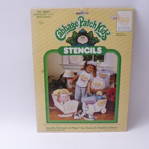 May include: Package of Cabbage Patch Kids stencils. The package shows a girl wearing a Cabbage Patch Kids shirt and holding a Cabbage Patch Kids doll. The package includes two 8 1/2 by 11 inch stencil sheets.