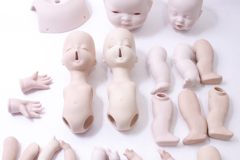 May include: A set of porcelain doll parts, including heads, torsos, legs, and arms. The parts are unpainted and ready to be customized.