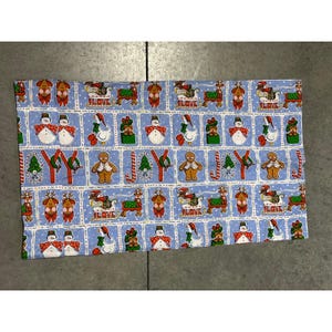 May include: A light blue Christmas-themed fabric with a repeating pattern of festive characters. The design includes snowmen, gingerbread men, reindeer, and geese, along with candy canes and Christmas trees. The word "LOVE" is also featured in the design.