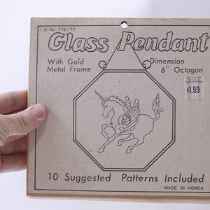 May include: A brown paper package with a white unicorn design and the text "Glass Pendant" and "10 Suggested Patterns Included". The package also includes the text "With Gold Metal Frame", "Dimension 6" Octagon", and "$1.99".