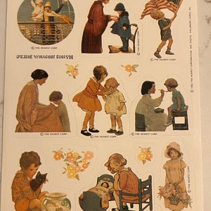 Pode incluir: Uma folha de adesivos de estilo vintage com ilustrações de crianças em várias cenas. Os adesivos são impressos em papel branco com uma borda azul clara. O texto "Jessie Willcox Smith" é impresso na parte superior da folha. O texto "The Hearst Corp." é impresso na parte inferior de cada adesivo.