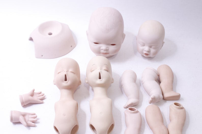May include: A set of porcelain doll parts, including heads, torsos, arms, and legs. The parts are unpainted and ready to be customized.