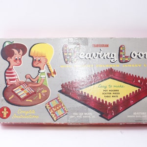 Könnte beinhalten: Eine Vintage-Transogram-Webstuhl-Box mit einem roten und weißen Webstuhl, bunten Jersey-Schlaufen und Illustrationen von zwei Kindern, die weben. Die Box enthält eine vollständige Anleitung und gibt an, dass Sie Topflappen, Streuteile und Tischsets weben können.