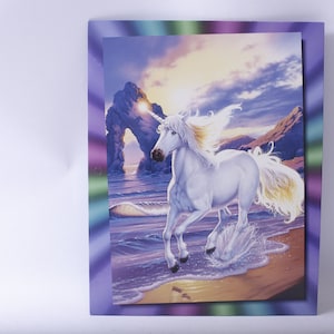May include: A white unicorn with a golden horn and mane runs through the surf on a beach with a rocky archway in the background. The sky is a vibrant purple and orange.