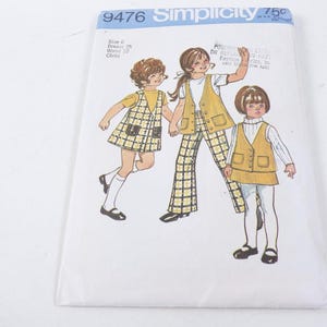 Può includere: Confezione di cartamodelli Simplicity con illustrazioni di abbigliamento per bambini. Il modello include un vestito, un gilet e pantaloni, tutti in un design a quadri gialli e neri. La confezione ha il numero 9476 e la parola "Simplicity".