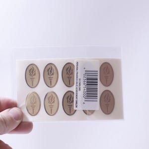 May include: A package of 50 gold-colored oval stickers with a torch design. The stickers are labeled "Personal Progress Value Achievement Emblem".