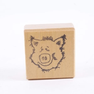 May include: A wooden block stamp with a black and white illustration of a pig's face.