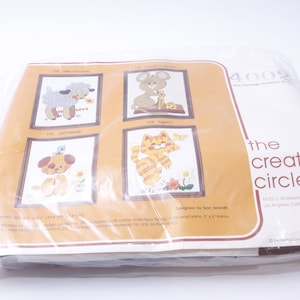 Può includere: Un pacchetto di kit da ricamo con quattro diversi disegni di animali: un agnello, un topo, un gatto e un cane. Il pacchetto è etichettato "The Creative Circle" e include le istruzioni per completare i progetti.