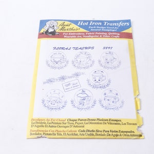 Puede incluir: Una hoja de papel blanca con un borde amarillo. El papel tiene una ilustración azul y roja de una mujer con un vestido y un delantal blanco. El texto "Aunt Martha's Hot Iron Transfers" está impreso en negro. El texto "Each Design Good for Several Stampings!" está impreso en negro. El texto "For Embroidery, Fabric Painting, Quilting, Wearable Art, Needlepoint & Other Crafts" está impreso en negro. El texto "Floral Teacups 3897" está impreso en negro. Hay siete imágenes de tazas de té con diseños florales impresos en el papel.