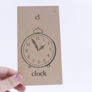 May include: A brown card with the word "cl" and a black and white illustration of a clock. The word "clock" is printed below the illustration.
