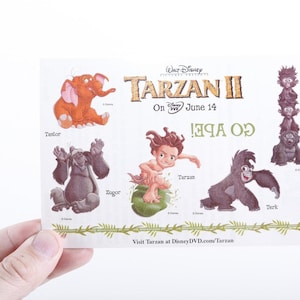 Może przedstawiać: Karta promocyjna do filmu Tarzan II Disneya, z postaciami z kreskówek, takimi jak Tarzan, Tantor i Zugor. Karta zawiera tytuł filmu i datę premiery, z tekstem "Go Ape!" oraz adresem strony internetowej.
