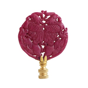 May include: A red jade finial with a carved design of two phoenixes and other mythical creatures. The finial is mounted on a gold-colored base.