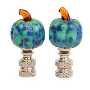 Puede incluir: Dos remates de lámpara de calabaza de vidrio azul y verde con tallos naranjas y bases plateadas.