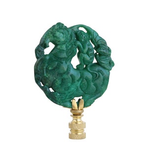 May include: Green jade lamp finial with a carved design of a monkey riding a horse. The finial is mounted on a gold-colored base.