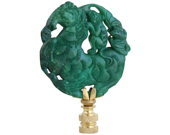 May include: Green jade lamp finial with a carved design of a monkey riding a horse. The finial is mounted on a gold-colored base.