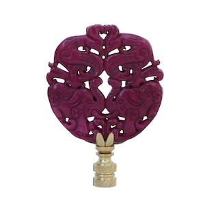 May include: A purple jade lamp finial with a carved design of two elephants facing each other. The finial is mounted on a gold-colored base.