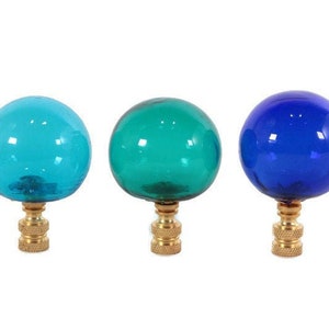 May include: Three glass finials in blue, teal, and turquoise colors. Each finial has a brass base.