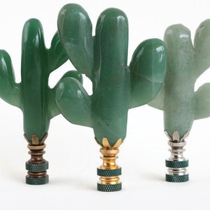 May include: Three green jade cactus finials with brass and silver bases. The finials are carved in the shape of a cactus with multiple arms.