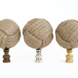 May include: Three decorative finials with a knotted rope design. The finials are made of natural jute rope and have a brass, nickel, and gold finish.