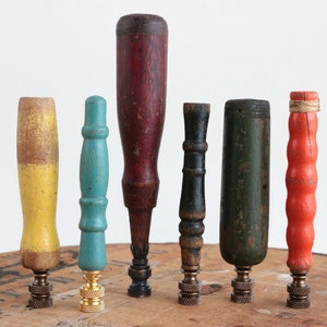 Könnte beinhalten: Sechs vintage Holzgriffe in verschiedenen Farben und Ausführungen, darunter rot, gelb, blau, grün und schwarz. Die Griffe sind auf Metallsockeln montiert.