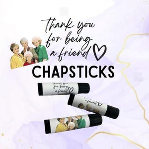 May include: Four lip balm tubes with a white label that says "Thank you for being a friend" with a heart symbol. The lip balms are on a purple and white background.