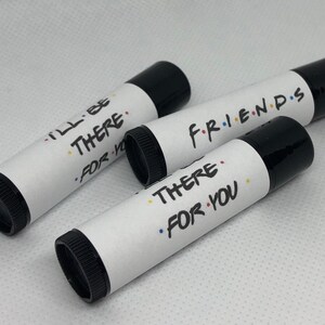 May include: Three black lip balm tubes with white labels. The labels have the text "I'll Be There For You", "There For You", and "Friends" with colorful dots.