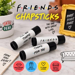 May include: Three white lip balm tubes with black caps, each featuring black text inspired by the TV show Friends. The tubes display phrases including I'll Be There For You and Friends, alongside colorful dots between letters on a white background.