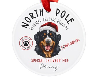 Può includere: Un ornamento natalizio rotondo e bianco con un nastro rosso. Presenta un Bovaro del Bernese con un cappello di Babbo Natale. Il testo include "North Pole Reindeer Express Delivery", "Approved by Santa Paws" e "Very Good Girl". L'ornamento è personalizzato con il nome "Penny".