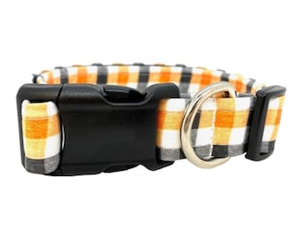 May include: Orange and gray plaid dog collar with a black plastic buckle and a silver metal D-ring.
