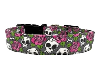 May include: A grey dog collar with a pattern of pink roses and white skulls. The collar has a black plastic buckle.