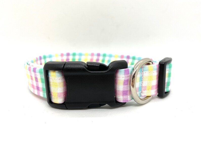 May include: A pastel pink, yellow, green, and blue plaid dog collar with a black plastic buckle and a silver metal D-ring.