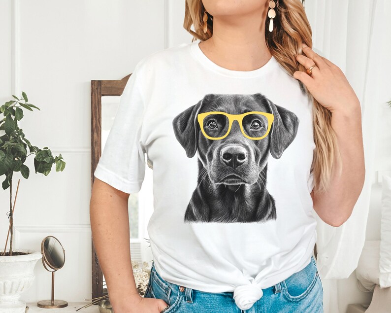 Pode incluir: Camiseta branca com uma ilustra&ccedil;&atilde;o em preto e branco de um Labrador Retriever usando &oacute;culos de sol amarelos.