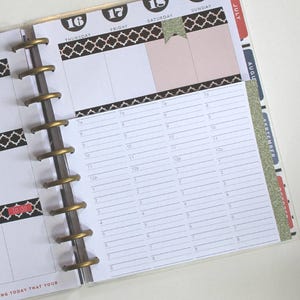 May include: A close-up of a weekly planner with a black and white patterned design. The planner is open to the week of July 16th through July 19th. The planner has a gold coil binding and a black and white patterned cover.