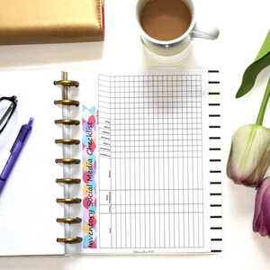 Peut inclure: Un agenda blanc avec une reliure &agrave; spirale dor&eacute;e et un autocollant color&eacute; qui dit "Inventory Social Media Checklist". L'agenda est ouvert sur une page avec un motif quadrill&eacute; et des lignes noires.