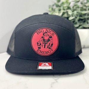 May include: Black and red flat bill trucker hat with a red circle logo that says "Big Nick Energy" and a cartoon Santa Claus inside the circle.