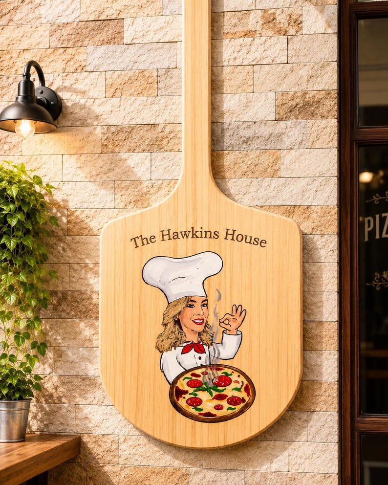 Może przedstawiać: Jasny drewniany szyld ścienny w kształcie łopaty do pizzy z napisem The Hawkins House. Grafika przedstawia kucharza w białej czapce i mundurze, wykonującego gest ok nad parującą pizzą z pepperoni, czerwoną sosem i roztopionym serem.