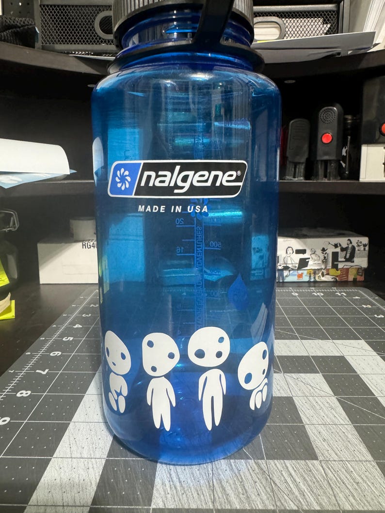 May include: A blue Nalgene water bottle with a white sticker of four white characters with black eyes. The sticker says "nalgene" and "MADE IN USA".