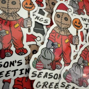 May include: A set of Christmas stickers featuring a creepy, stitched-faced character wearing a Santa hat and holding a candy cane. The stickers have different designs, including the character holding a bag of presents, and text that says "Season's Greetings".