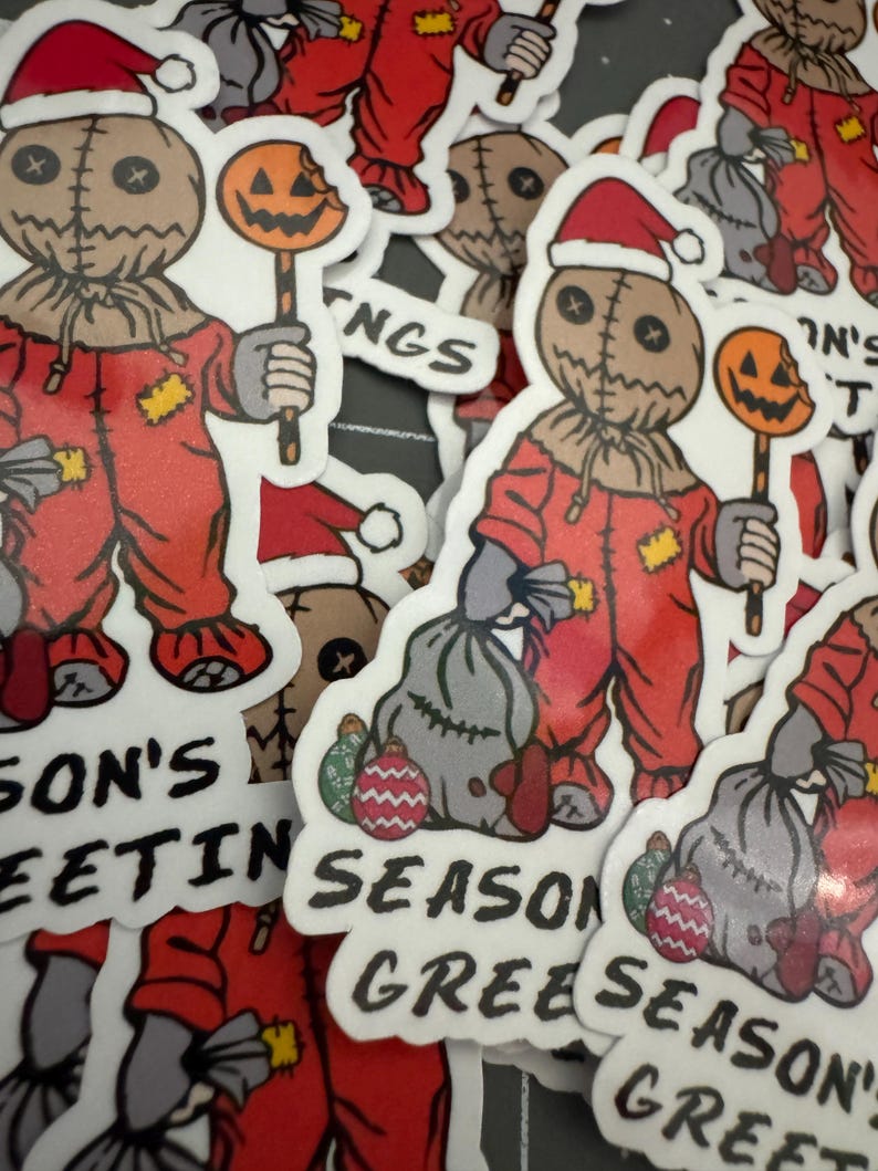 May include: A set of Christmas stickers featuring a creepy, stitched-faced character wearing a Santa hat and holding a candy cane. The stickers have different designs, including the character holding a bag of presents, and text that says "Season's Greetings".