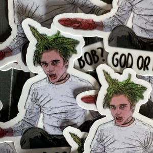 May include: A set of stickers featuring a character with green hair and a white shirt. The stickers have the text "BOB? GOD OR" and "GOD OR" on them.