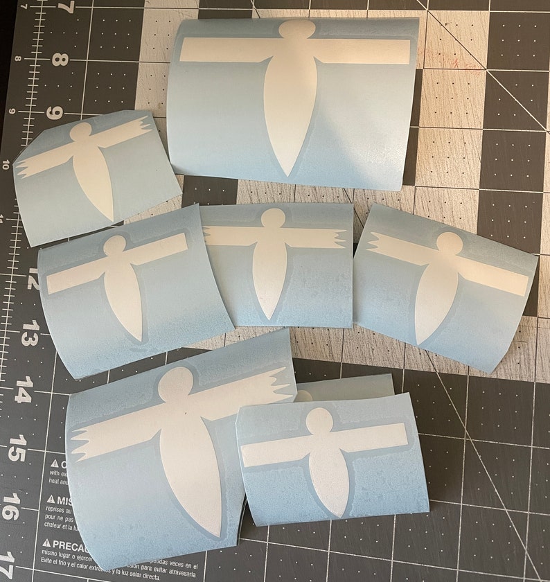 May include: A set of eight white vinyl decals in the shape of a person with outstretched arms. The decals are on a light blue background.